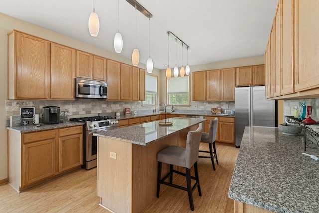 16260 W Mohawk Ct, Lockport, IL 60441 - kitchen featuring stainless steel appliances, light wood-style flooring, a kitchen breakfast bar, a kitchen island, and tasteful backsplash
