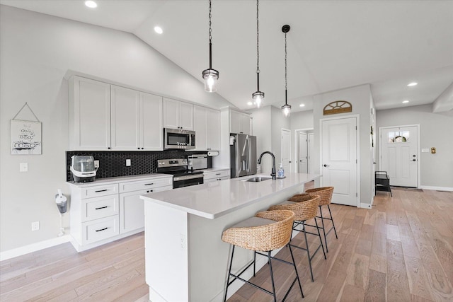 3610 Freedom Blvd, Champaign, IL 61822 - kitchen with stainless steel appliances, an island with sink, a breakfast bar area, light wood-style flooring, and white cabinets