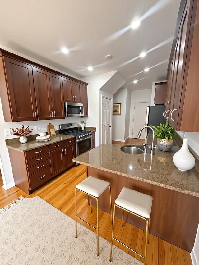1659 Windward Ct, Naperville, IL 60563 - kitchen with stainless steel appliances, a peninsula, light wood-type flooring, light stone counters, and a breakfast bar