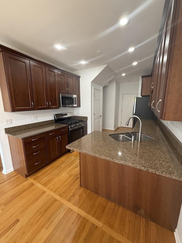 1659 Windward Ct, Naperville, IL 60563 - kitchen with stainless steel appliances, dark stone counters, light wood-type flooring, dark brown cabinetry, and a peninsula