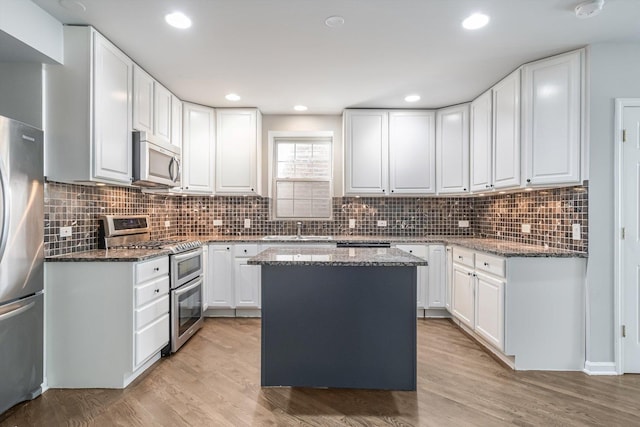 2726 W Thomas St, Chicago, IL 60622 - kitchen featuring stainless steel appliances, dark stone countertops, white cabinetry, light wood-style floors, and recessed lighting