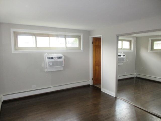 2012 W 111th St Unit 3S, Chicago, IL 60643 - spare room featuring a baseboard radiator, an AC wall unit, dark wood-style floors, and baseboard heating