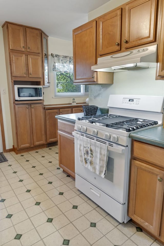 509 Waverly Ave, Streamwood, IL 60107 - kitchen with white range with gas cooktop, under cabinet range hood, stainless steel microwave, and brown cabinets