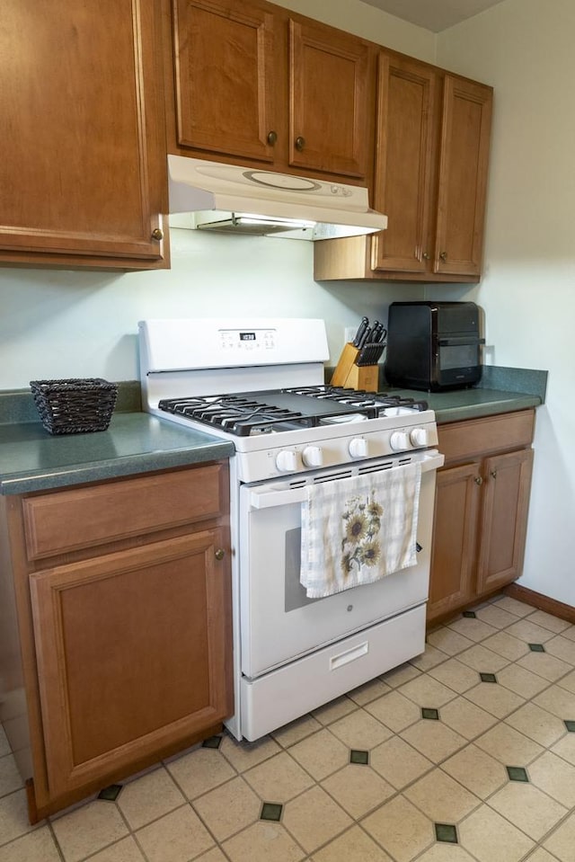 509 Waverly Ave, Streamwood, IL 60107 - kitchen with white gas range, under cabinet range hood, dark countertops, brown cabinets, and light tile patterned flooring