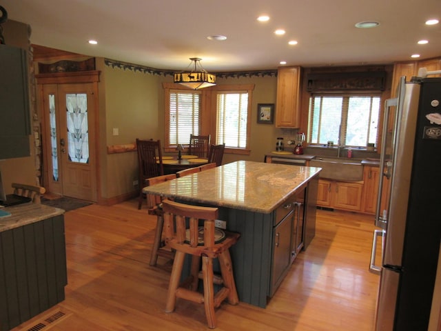 24099 W Haidi Ln, Lake Villa, IL 60046 - kitchen with freestanding refrigerator, light wood-style floors, a kitchen island, recessed lighting, and a breakfast bar area