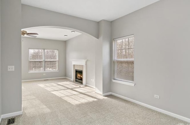533 Jackson Blvd, Grayslake, IL 60030 - unfurnished living room with carpet, a fireplace with flush hearth, arched walkways, and a ceiling fan