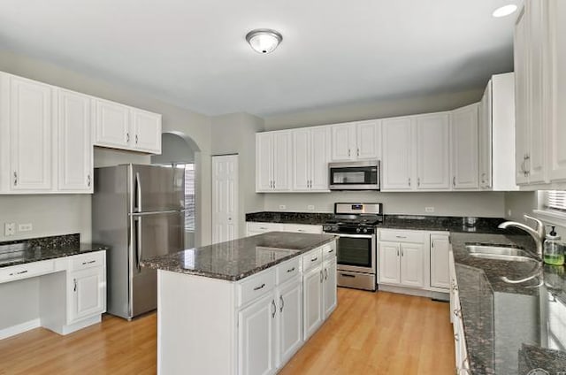 533 Jackson Blvd, Grayslake, IL 60030 - kitchen with appliances with stainless steel finishes, arched walkways, light wood-style floors, a center island, and white cabinetry