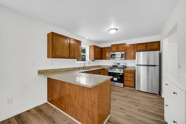 643 N Bridgeport Ter, Lindenhurst, IL 60046 - kitchen with stainless steel appliances, a peninsula, brown cabinetry, light wood-style flooring, and light stone counters