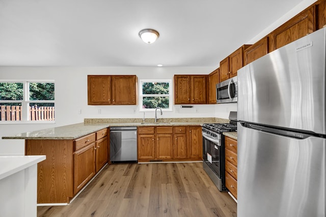 643 N Bridgeport Ter, Lindenhurst, IL 60046 - kitchen with appliances with stainless steel finishes, a peninsula, brown cabinets, light wood-type flooring, and healthy amount of natural light