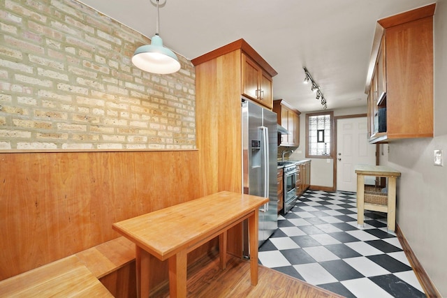 2753 N Spaulding Ave Unit Gs, Chicago, IL 60647 - kitchen with dark flooring, stainless steel appliances, track lighting, wooden walls, and brown cabinets