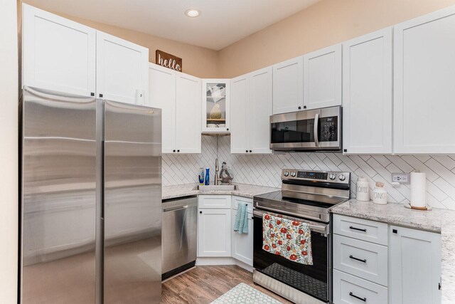 2308 Maple Ln, Rolling Meadows, IL 60008 - kitchen with appliances with stainless steel finishes, white cabinets, tasteful backsplash, glass insert cabinets, and light stone counters
