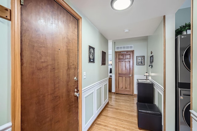 28 S 6th Ave Unit 1D, La Grange, IL 60525 - laundry area featuring stacked washer and clothes dryer, a decorative wall, light wood finished floors, and wainscoting