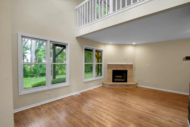 1921 Wisteria Ct Unit 3, Naperville, IL 60565 - unfurnished living room featuring wood finished floors, a tile fireplace, and a towering ceiling