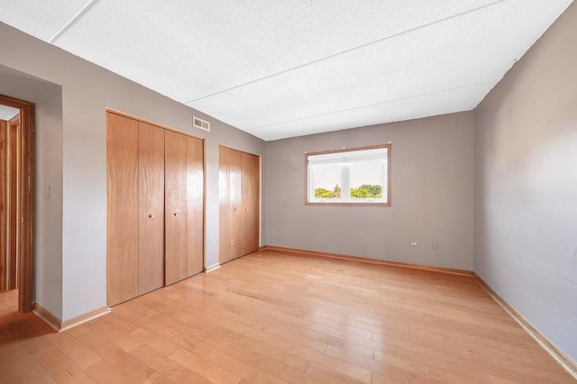 16719 Paxton Ave Unit 2S, Tinley Park, IL 60477 - unfurnished bedroom with multiple closets, light wood finished floors, and a textured ceiling