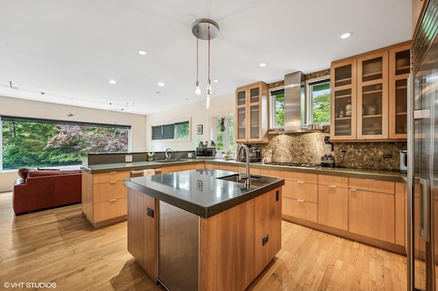 311 3rd St, Wilmette, IL 60091 - kitchen with a peninsula, wall chimney exhaust hood, dark countertops, a center island with sink, and light wood-style flooring
