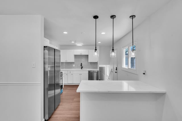 246 Gentry St, Park Forest, IL 60466 - kitchen with appliances with stainless steel finishes, a peninsula, white cabinets, light stone counters, and backsplash