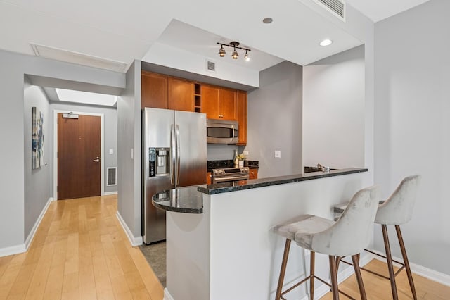 130 N Garland Ct Unit 1608, Chicago, IL 60602 - kitchen with appliances with stainless steel finishes, light wood finished floors, brown cabinets, a kitchen breakfast bar, and dark stone counters