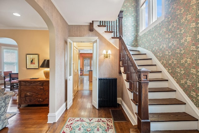 611 Lake Ave, Wilmette, IL 60091 - stairway with radiator, wallpapered walls, plenty of natural light, wood finished floors, and arched walkways