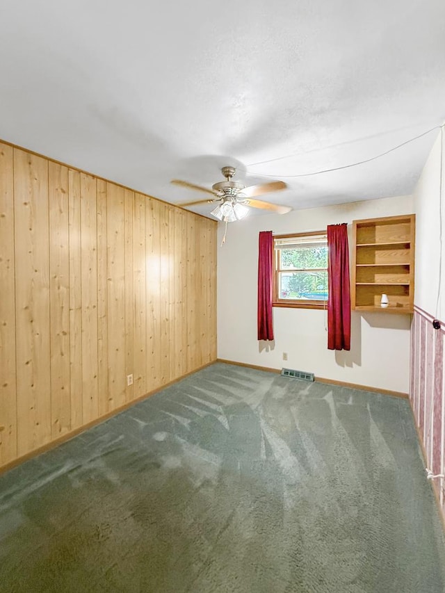 207 Southview Dr, Rochelle, IL 61068 - empty room featuring a ceiling fan, wooden walls, and carpet flooring