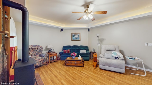 1513 Berwyn St, Spring Grove, IL 60081 - living room featuring light wood-style flooring, ceiling fan, a wood stove, and a tray ceiling
