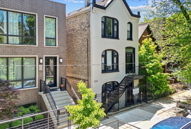2233 W Shakespeare Ave Unit 1F, Chicago, IL 60647 - view of front of house featuring stairs, brick siding, and stucco siding