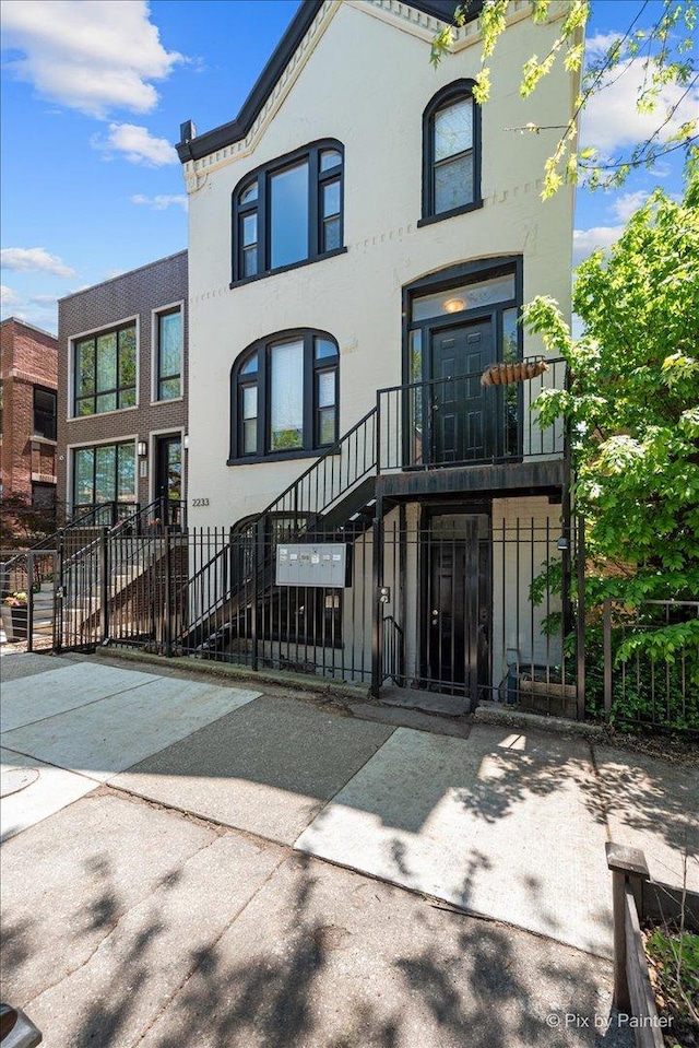 2233 W Shakespeare Ave Unit 1F, Chicago, IL 60647 - view of front of home with a fenced front yard, stucco siding, stairway, and a gate