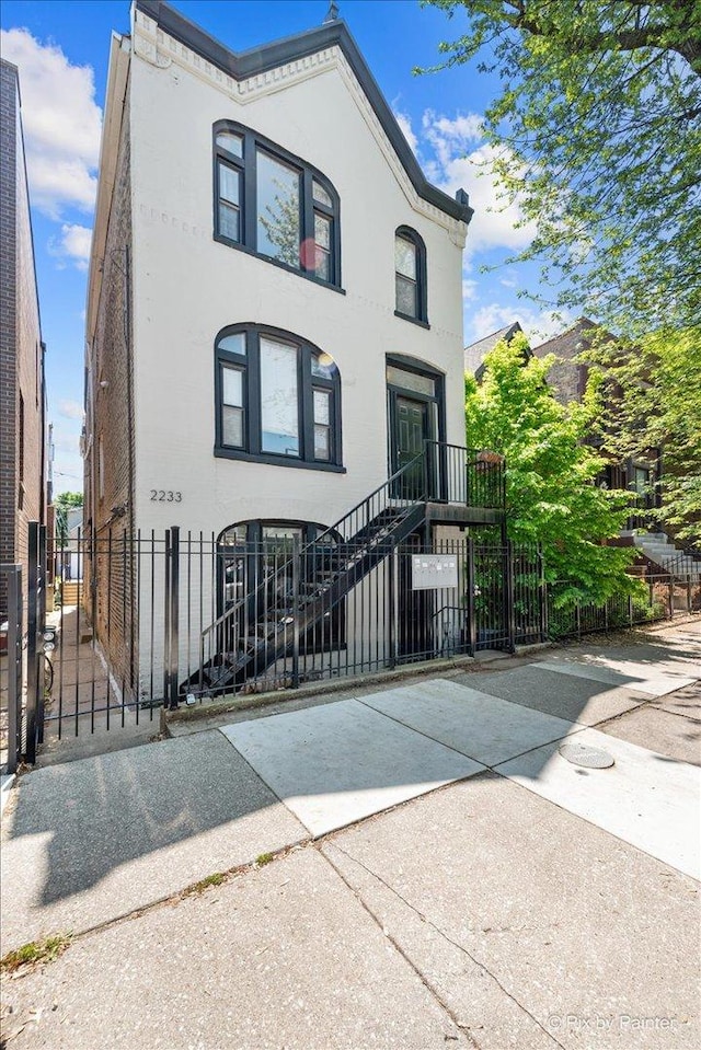 2233 W Shakespeare Ave Unit 1F, Chicago, IL 60647 - view of front facade with a gate, a fenced front yard, and stucco siding