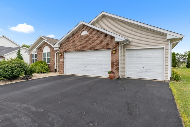 3792 Foxglove Ln, Winnebago, IL 61088 - view of front of home featuring an attached garage, asphalt driveway, and brick siding