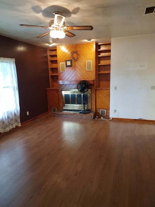 501 S Spruce St, Villa Grove, IL 61956 - unfurnished living room featuring wooden walls, wood finished floors, a fireplace, and ceiling fan