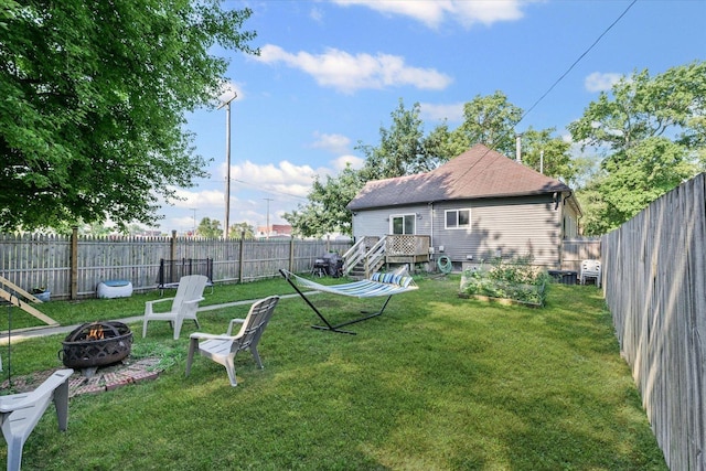 201 N Sycamore St, Villa Grove, IL 61956 - fenced backyard featuring a fire pit, a wooden deck, and a vegetable garden