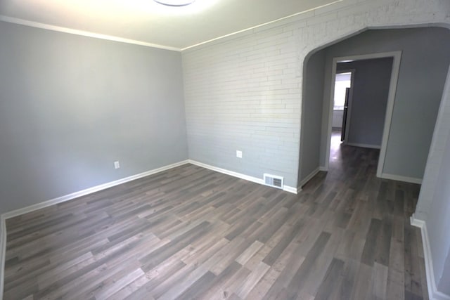 2524 N Mont Clare Ave, Chicago, IL 60707 - spare room with dark wood-style floors, brick wall, ornamental molding, and arched walkways