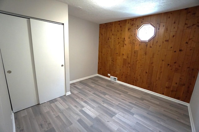 2524 N Mont Clare Ave, Chicago, IL 60707 - unfurnished bedroom featuring wood walls, wood finished floors, a textured ceiling, and a closet