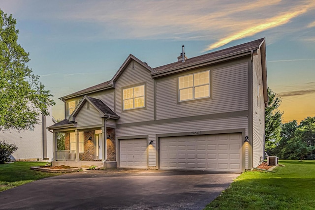 2054 S Jonathan Dr, Round Lake, IL 60073 - traditional-style home with a garage, asphalt driveway, a front lawn, and a porch