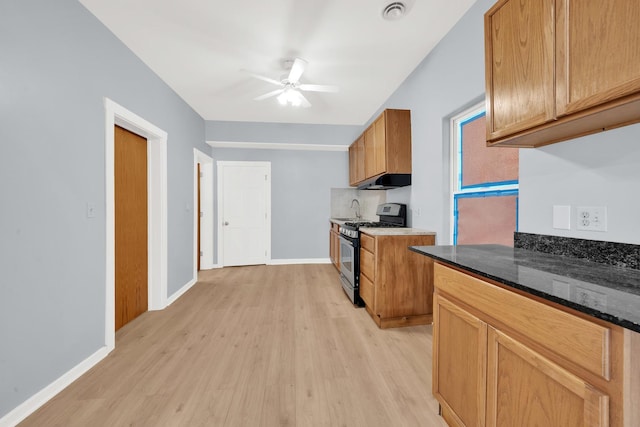 3826 S Honore St, Chicago, IL 60609 - kitchen with stainless steel gas range, light wood-style flooring, a ceiling fan, under cabinet range hood, and dark stone countertops