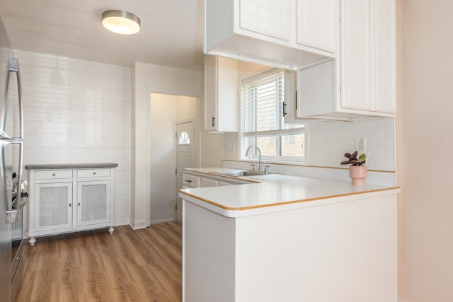 3345 N Page Ave, Chicago, IL 60634 - kitchen with wood finished floors, a peninsula, white cabinetry, light countertops, and backsplash