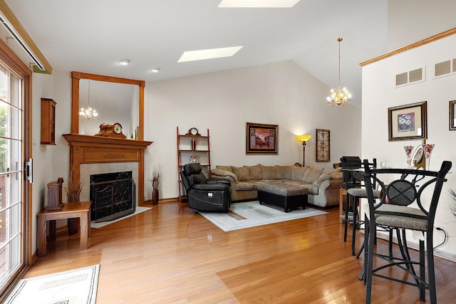 7672 Thistlewood Ln, Frankfort, IL 60423 - living area featuring light wood finished floors, a fireplace, a chandelier, vaulted ceiling, and a skylight