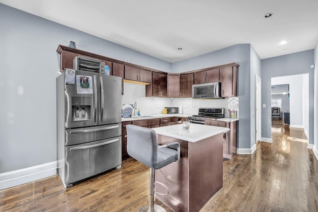 7627 S Prairie Ave, Chicago, IL 60619 - kitchen featuring stainless steel appliances, tasteful backsplash, light countertops, dark wood-style flooring, and a kitchen island