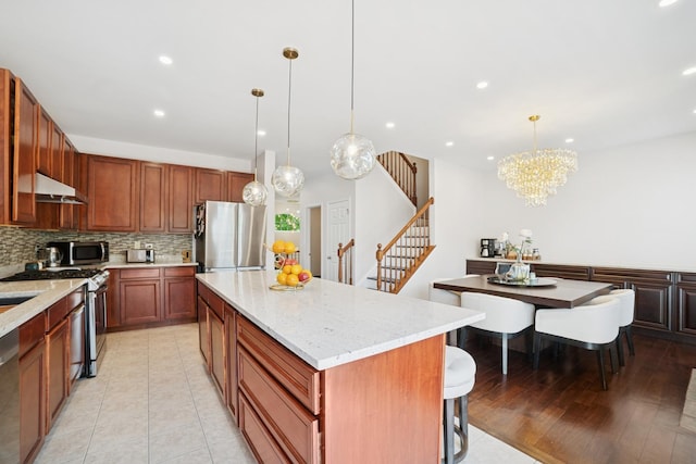 234 Cassidy Ln, Elgin, IL 60124 - kitchen with stainless steel appliances, under cabinet range hood, a center island, decorative backsplash, and recessed lighting