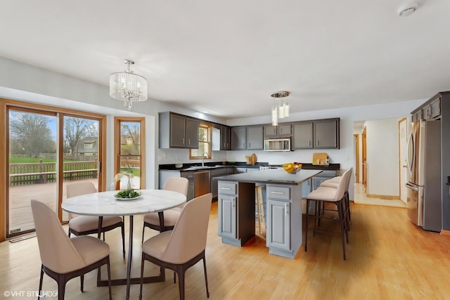13714 S Janas Pkwy, Homer Glen, IL 60491 - kitchen with appliances with stainless steel finishes, dark countertops, a center island, a chandelier, and light wood-style floors