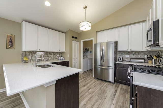 1444 Baroque Ave, Volo, IL 60073 - kitchen with appliances with stainless steel finishes, washer and dryer, a peninsula, light wood-style flooring, and tasteful backsplash