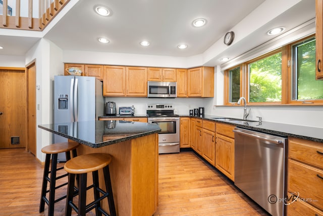 7 Vista Ridge Dr, Galena, IL 61036 - kitchen featuring appliances with stainless steel finishes, light wood-style floors, a breakfast bar, dark stone countertops, and a center island