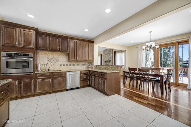 404 W Camp Mcdonald Rd, Prospect Heights, IL 60070 - kitchen featuring appliances with stainless steel finishes, a chandelier, light tile patterned flooring, backsplash, and light stone counters