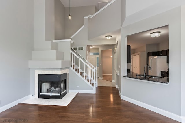 5584 Lavender Ct, Rolling Meadows, IL 60008 - unfurnished living room featuring stairway, wood finished floors, a towering ceiling, and a tiled fireplace