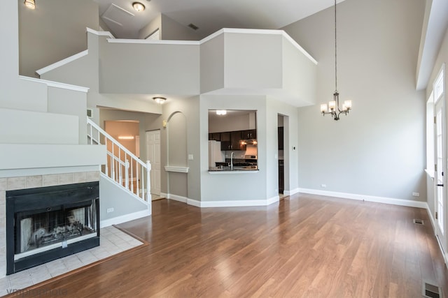 5584 Lavender Ct, Rolling Meadows, IL 60008 - unfurnished living room featuring a towering ceiling, wood finished floors, stairway, a chandelier, and a tiled fireplace