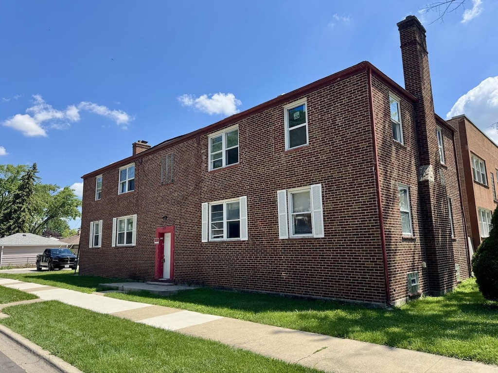 915 Bellwood Ave, Bellwood, IL 60104 - view of front facade with a chimney, brick siding, and a front yard