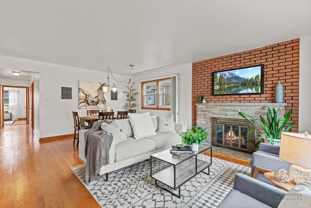 7025 W Berwyn Ave, Chicago, IL 60656 - living room featuring hardwood / wood-style flooring, a brick fireplace, and a chandelier