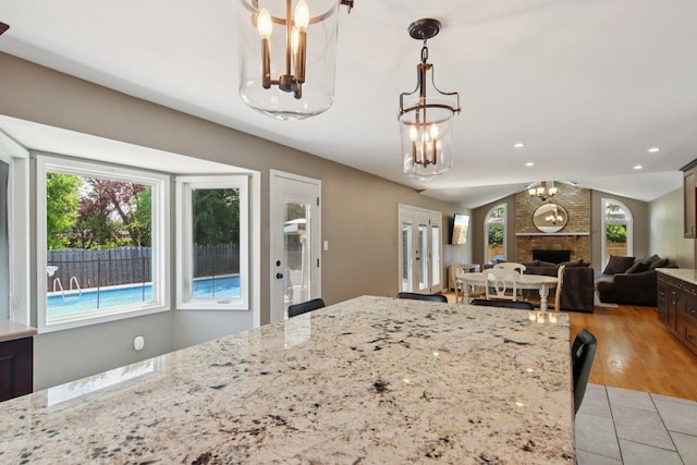 10215 S 87th Ct, Palos Hills, IL 60465 - kitchen featuring a chandelier, lofted ceiling, a brick fireplace, decorative light fixtures, and open floor plan