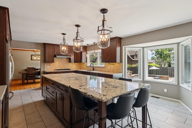 10215 S 87th Ct, Palos Hills, IL 60465 - kitchen with gas stovetop, under cabinet range hood, tasteful backsplash, and a chandelier