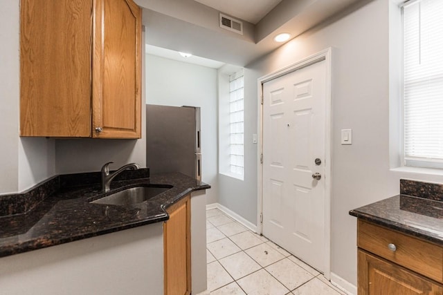 4008 W Nelson St Unit 8A, Chicago, IL 60641 - kitchen featuring freestanding refrigerator, dark stone counters, light tile patterned flooring, and brown cabinetry