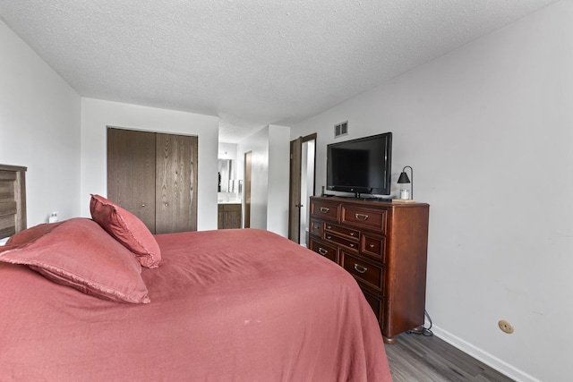 15141 Quail Hollow Dr Unit 106, Orland Park, IL 60462 - bedroom featuring dark wood-type flooring, a closet, a textured ceiling, and connected bathroom